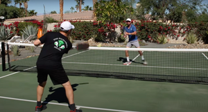 Two players practicing pickleball volleys at the kitchen line, focusing on lateral movement.