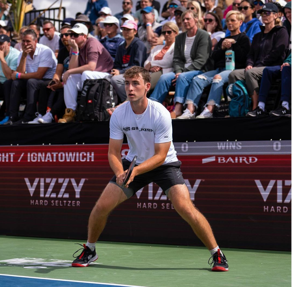 Dylan Frazier preparing to receive a serve during a match, with 'VIZZY HARD SELTZER' visible in the background.