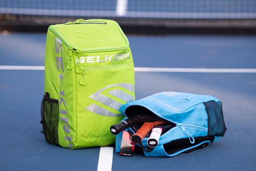 Two pickleball bags, one green and one blue, with paddles visible inside the blue bag.