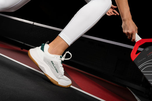 A close-up of a player wearing pickleball shoes while preparing to hit a ball.