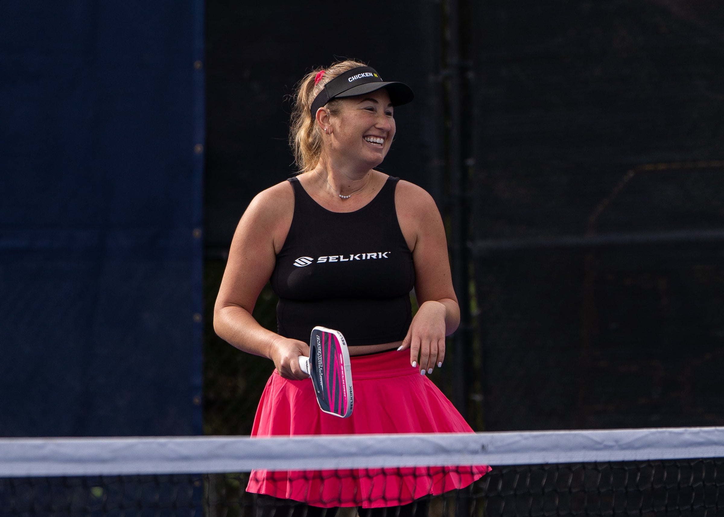 Lauren Stratman smiles on an outdoor pickleball court, holding a Selkirk Power Air paddle.