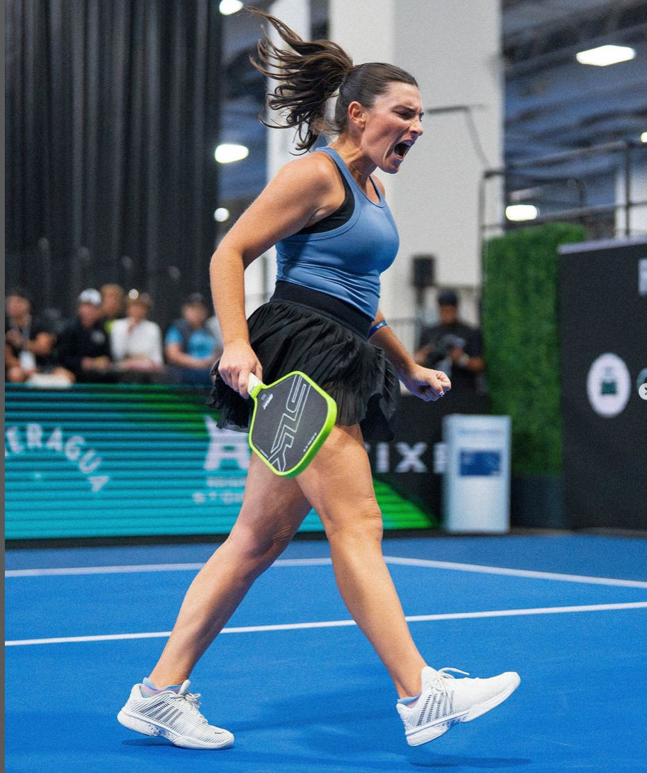 Rachel Rohrabacher celebrating her 5th title win, wearing a blue top and black skirt, on the court.