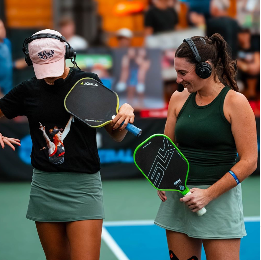 Anna Bright and Rachel Rohrabacher celebrating after winning the women's doubles finals, holding paddles and smiling.