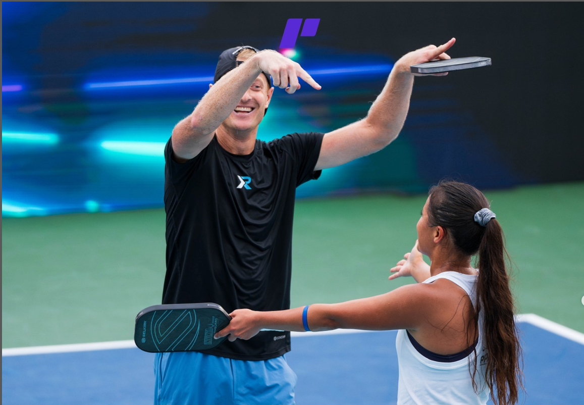 A male pickleball player celebrating with Jackie Kawamoto after a match, both holding paddles.