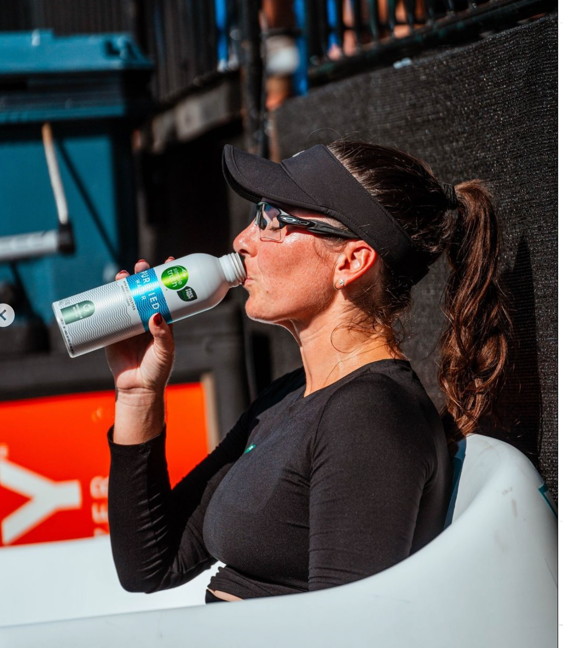 A female pickleball player drinking water during a match.
