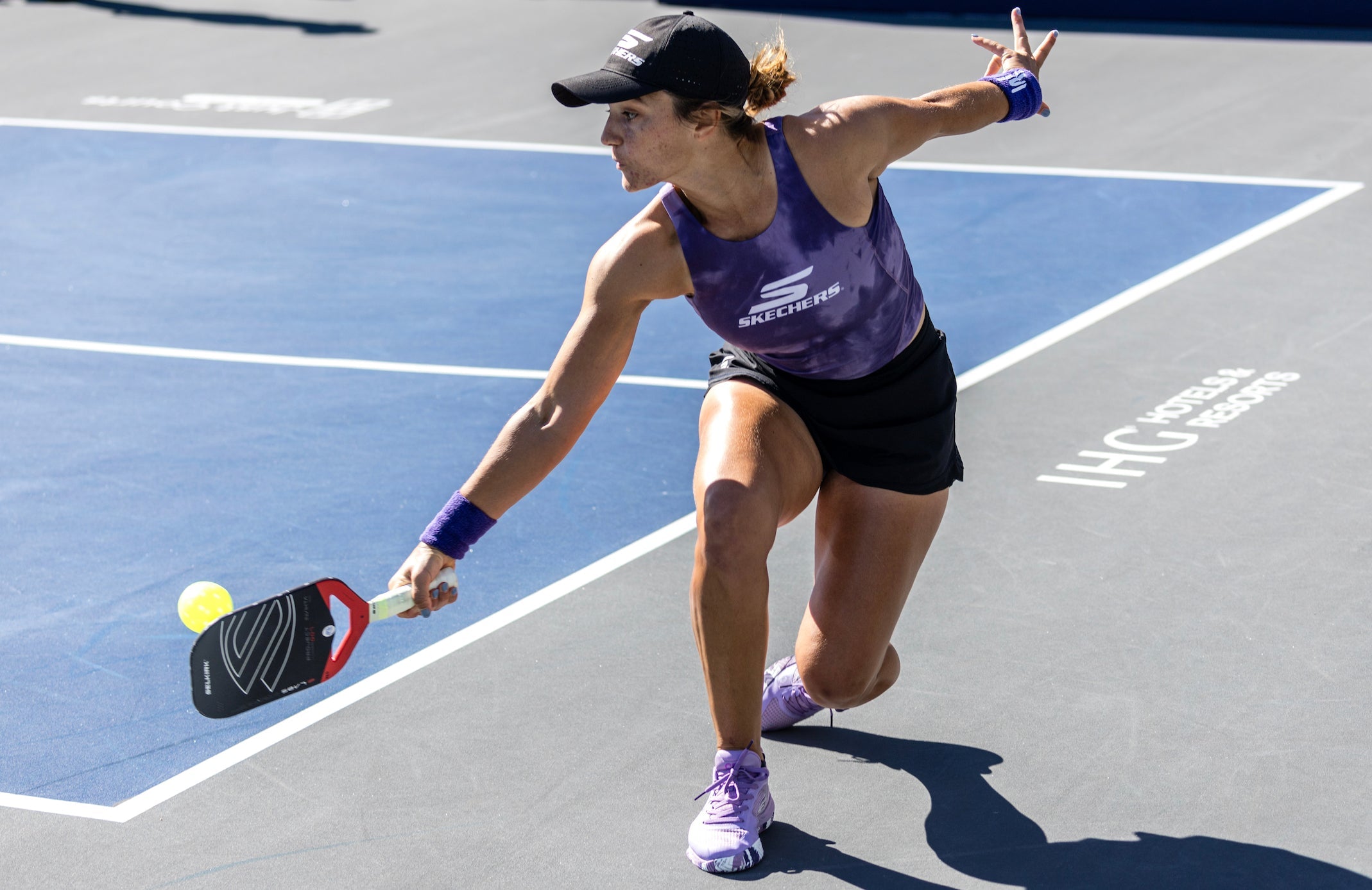 A female pickleball player in action, wearing a Team Selkirk uniform, on a court.