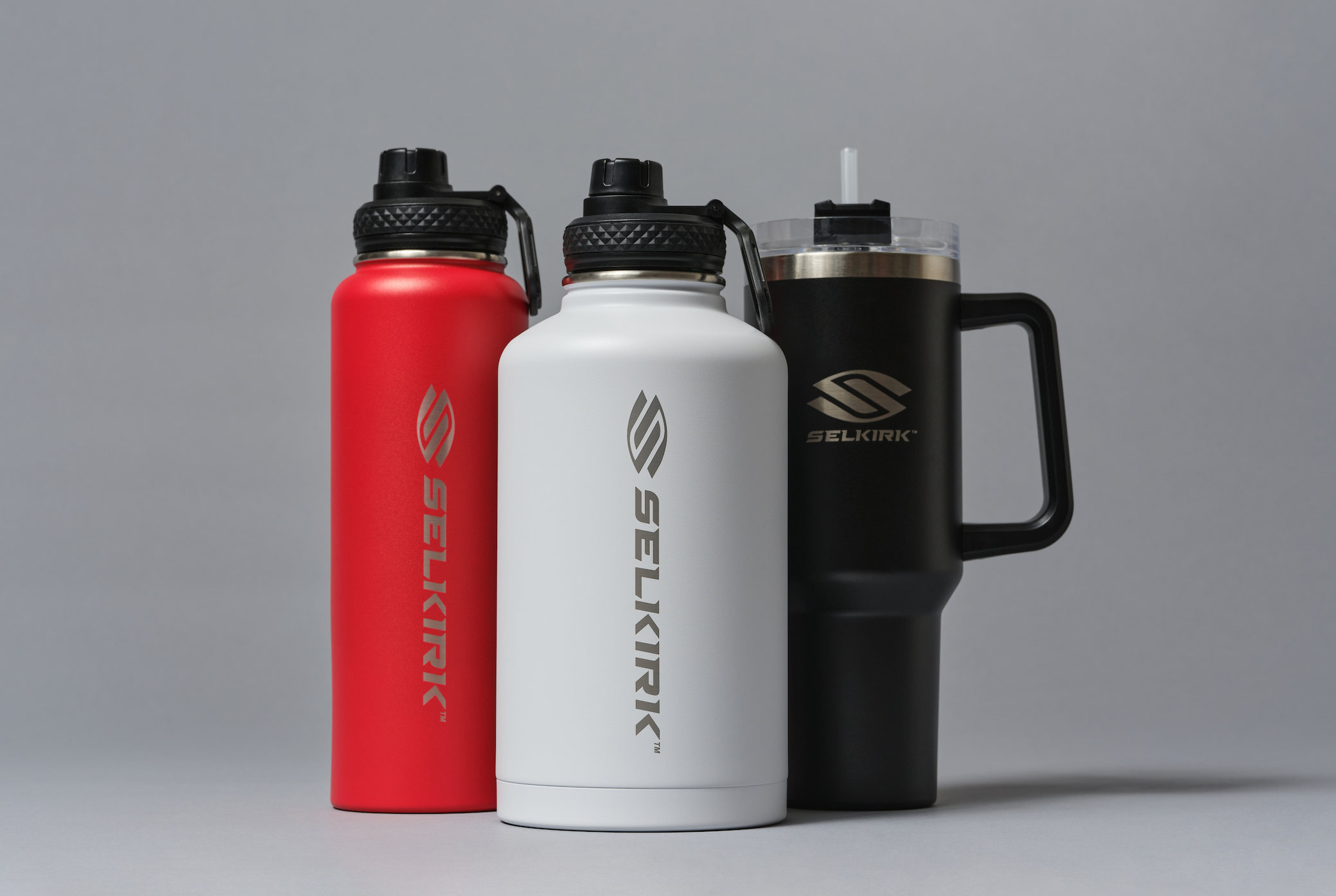Three water bottles in red, white, and black, showcasing hydration options for pickleball players.