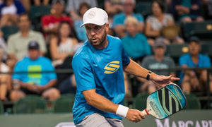 Morgan Evans playing pickleball in a blue shirt and white cap.