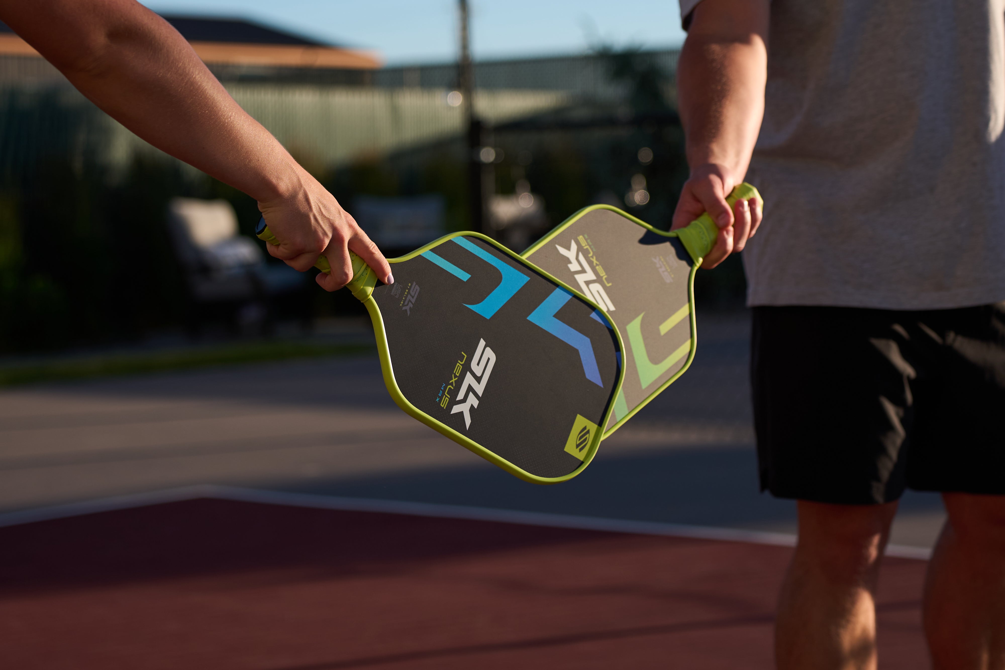 Two pickleball paddles being held by players on a court.