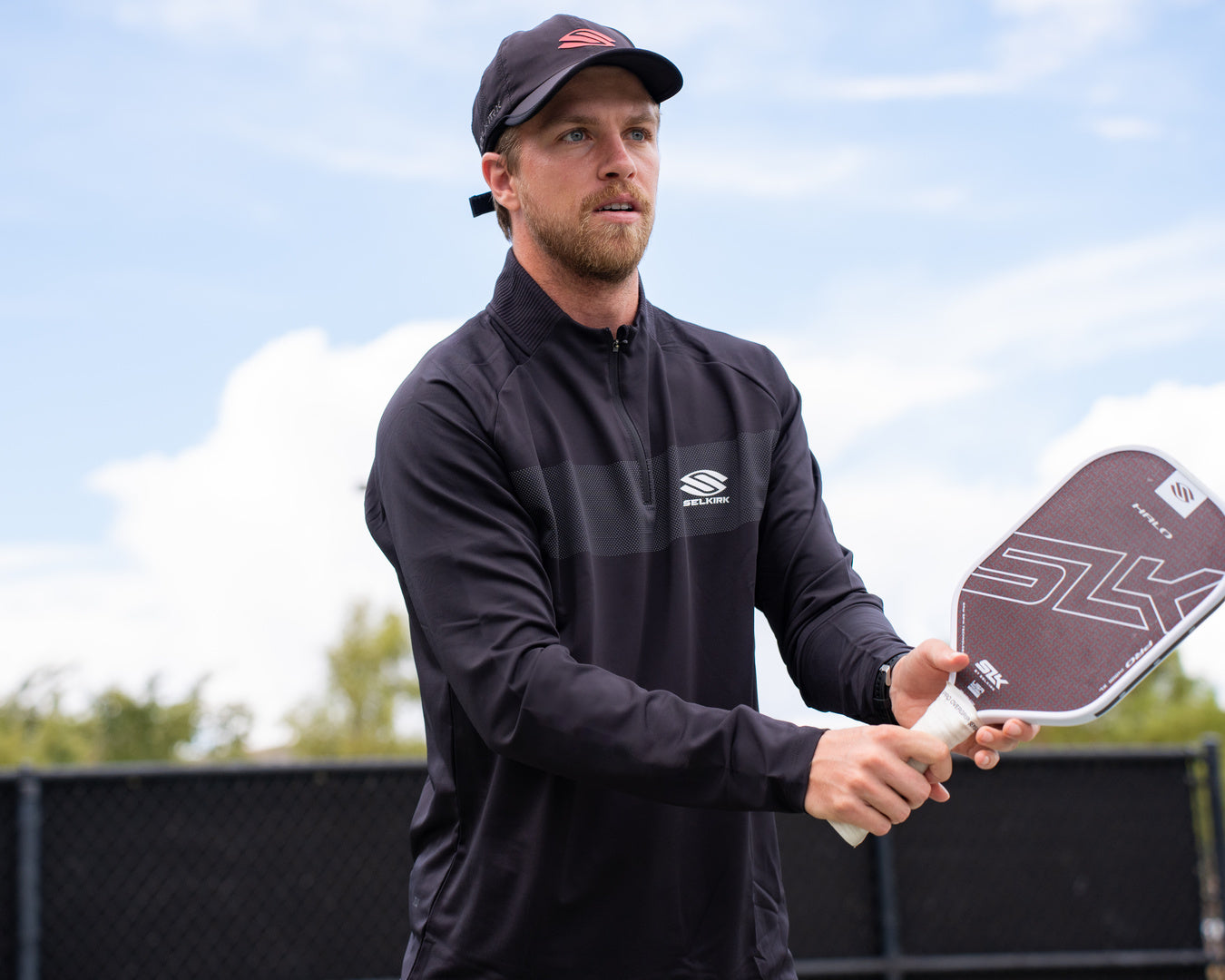 A man preparing for a volley shot with a SLK Halo Pro pickleball paddle, showcasing its design and grip.