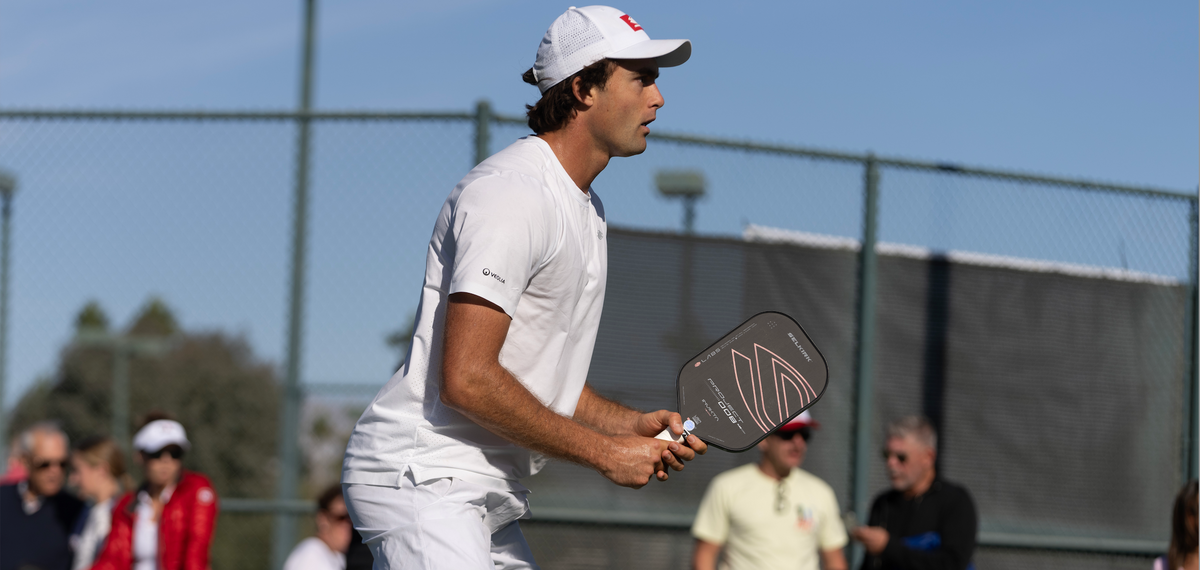 Pickleball player in white holding a Selkirk paddle on an outdoor court