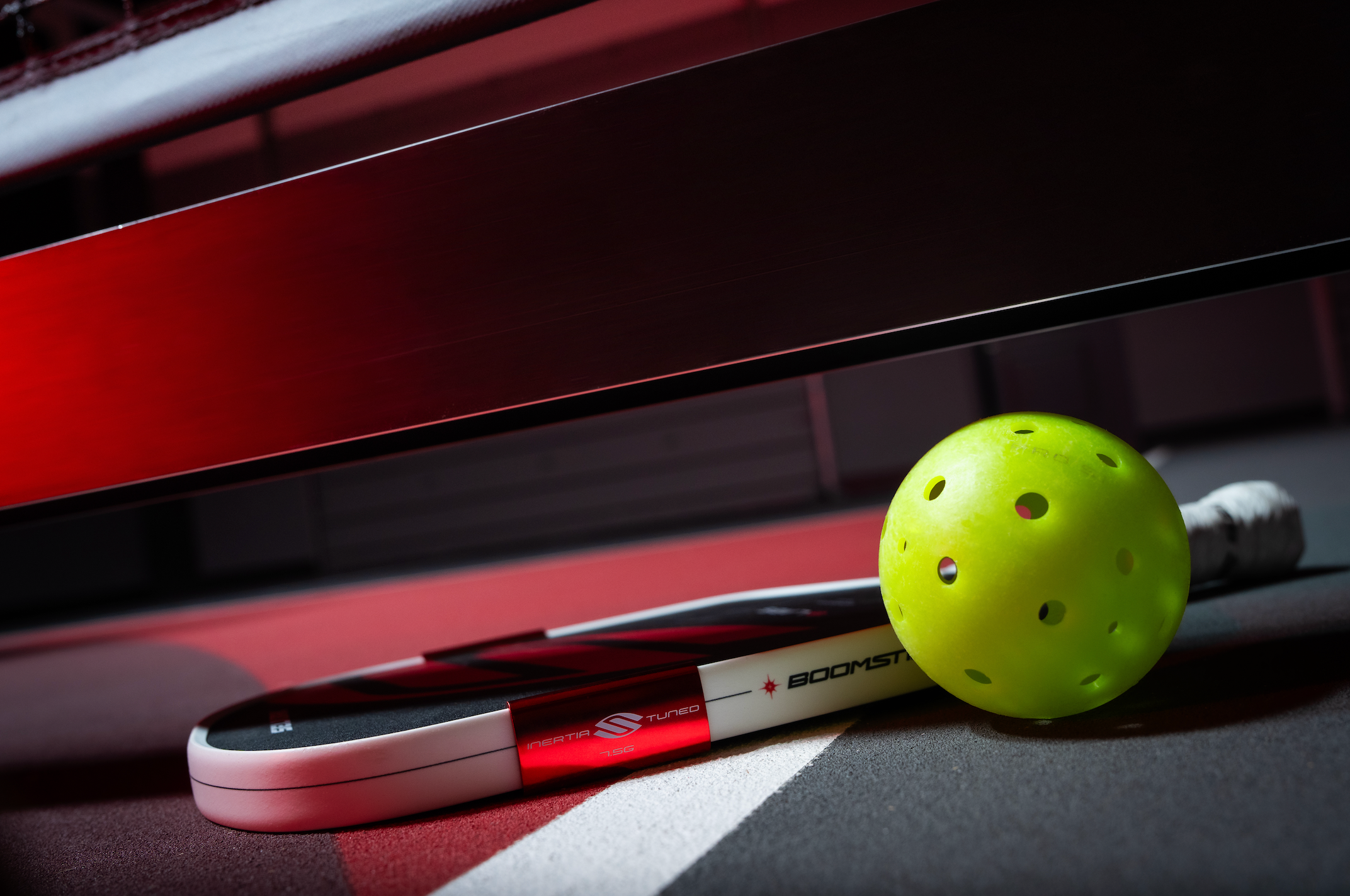 A Boomstik and a Pro S1 sit next to each other on an indoor pickleball court. 