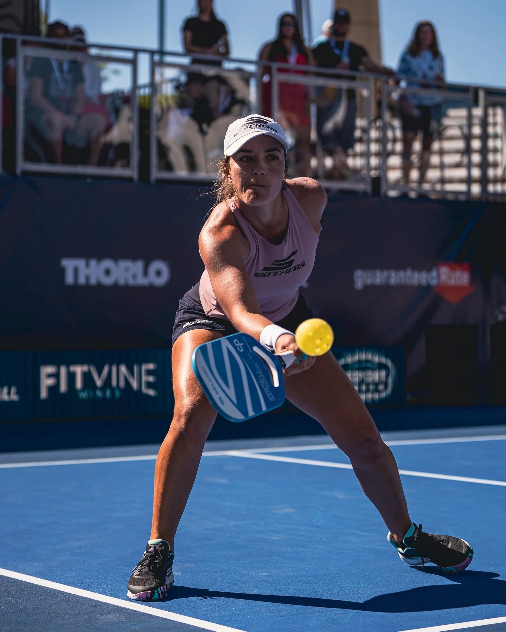 A female player in action on a pickleball court, preparing to hit a ball with a paddle.