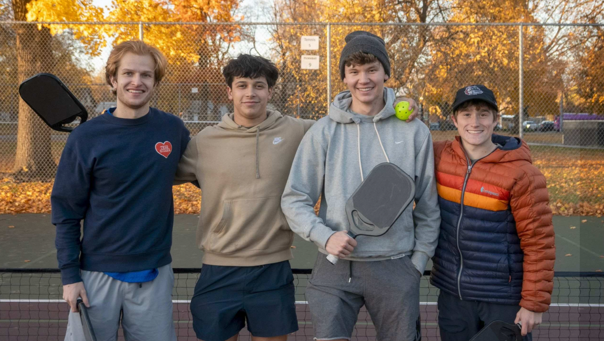 Jack David, Ashton Bischoff, Ryan Spuck, and Luke Alfonso smile while holding unmarked pickleball paddles. 