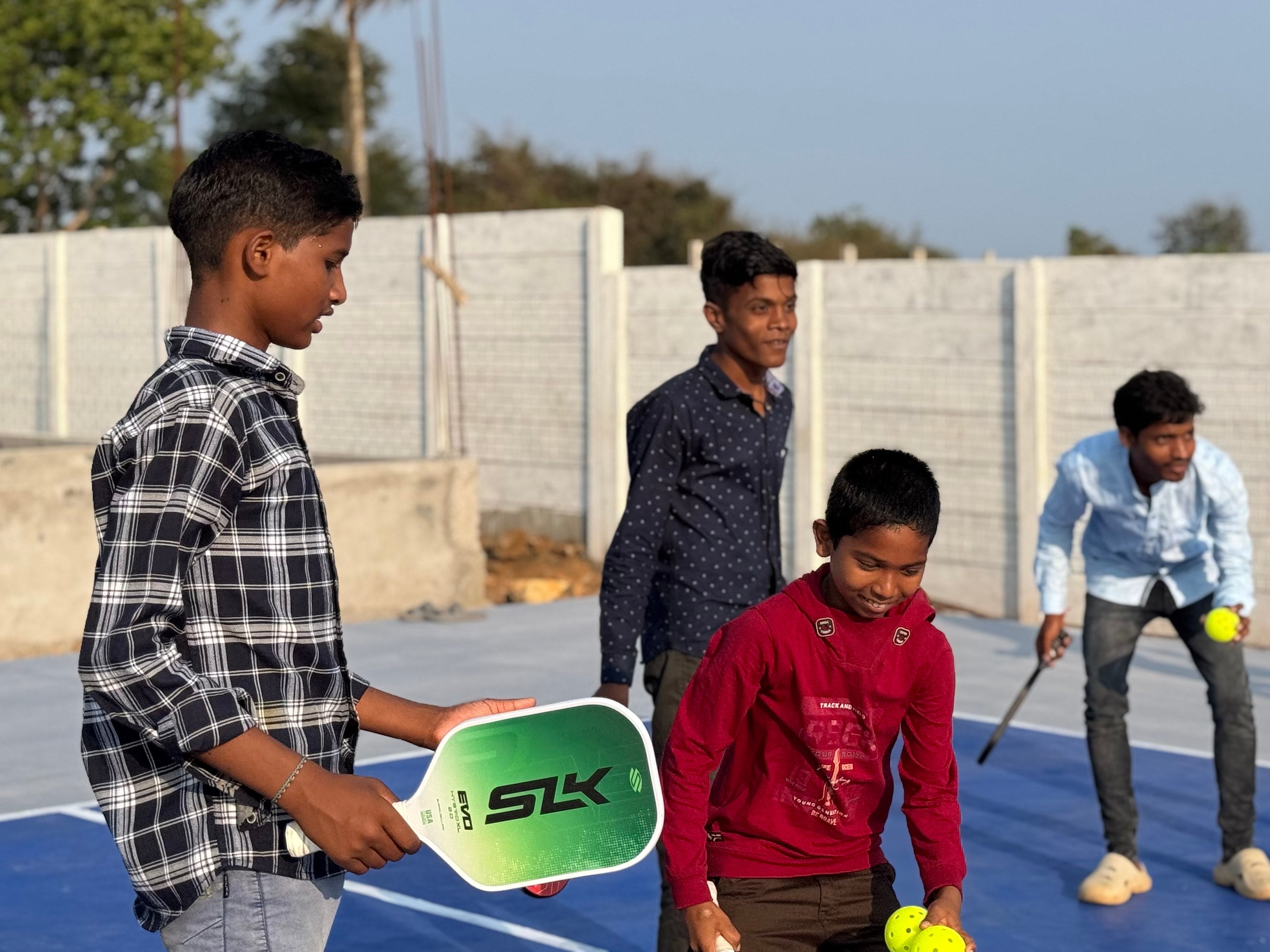Several children in India play pickleball with Selkirk paddles. 