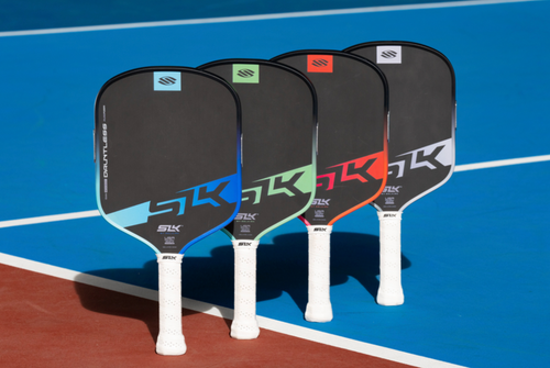 Four colorways of the SLK Dauntless stand in a line on a pickleball court. 