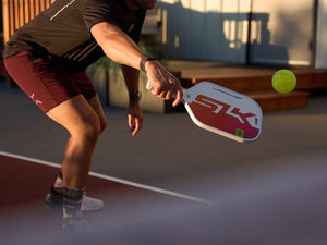 A man completes a volley shot with his SLK Latitude pickleball paddle. 