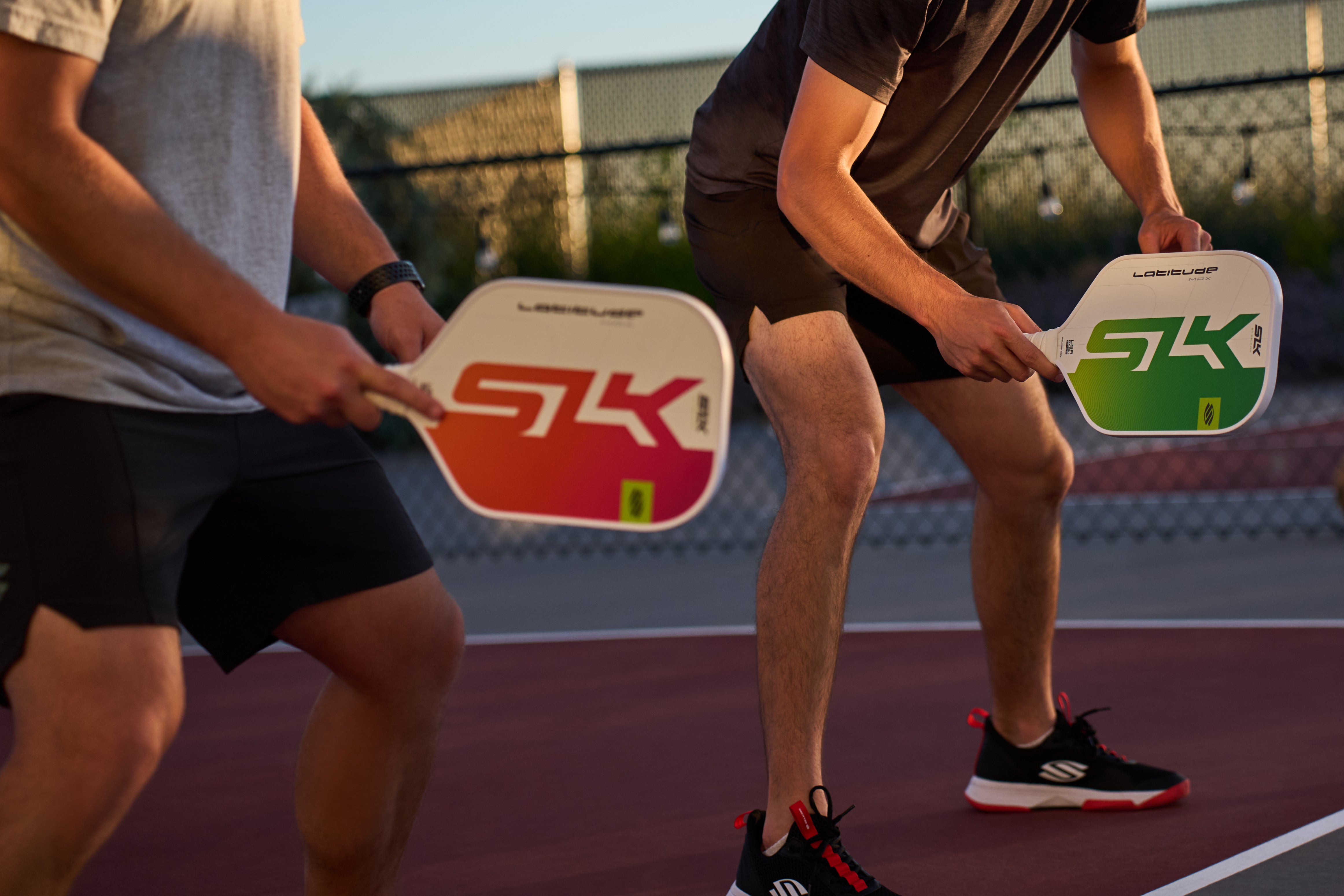 Two pickleball players practicing with paddles on a court.
