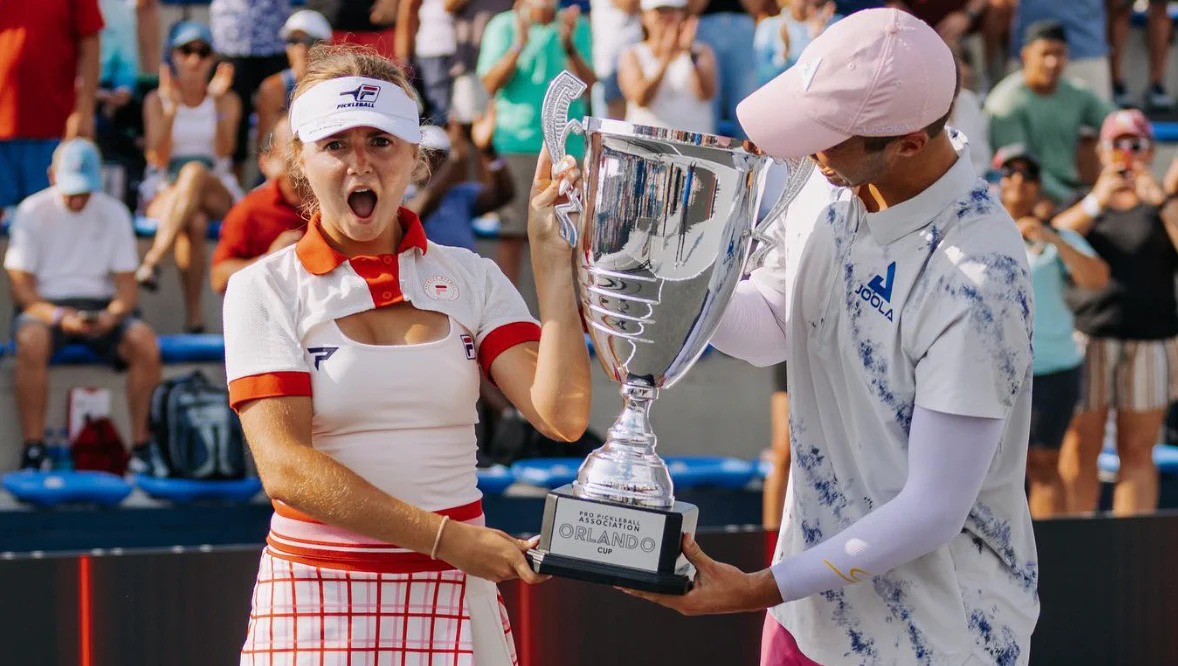 Two players celebrating with a trophy after winning a tournament.
