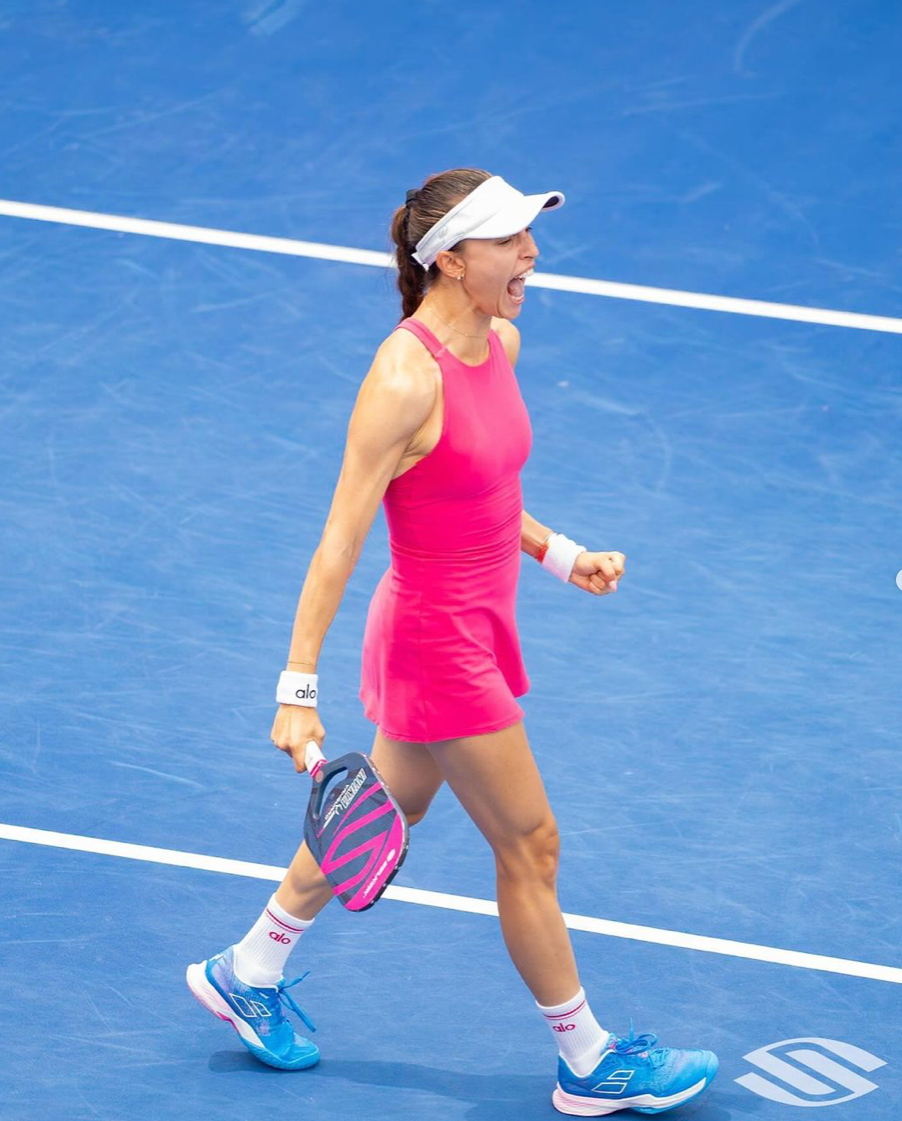 Female pickleball player in a pink outfit celebrating on the court