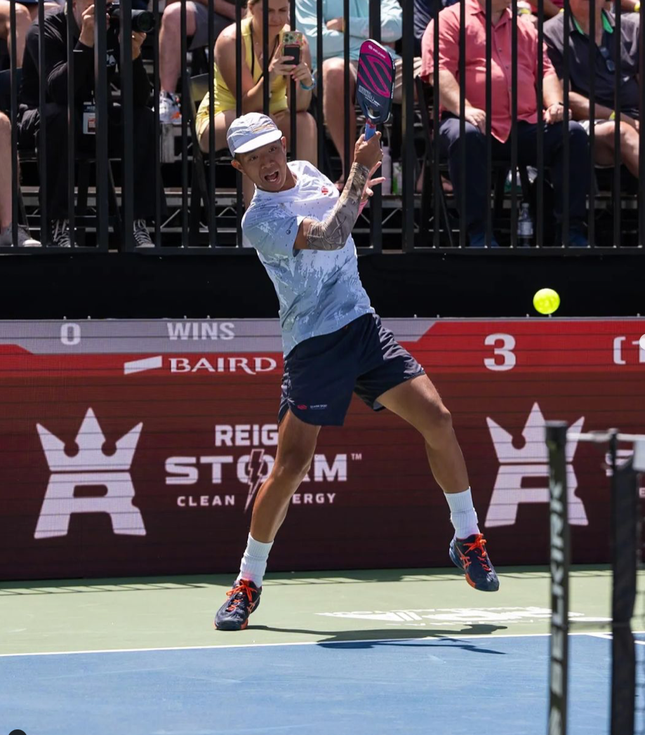 Quang Duong hitting a pickleball shot during a match, with scoreboard showing 0-3.