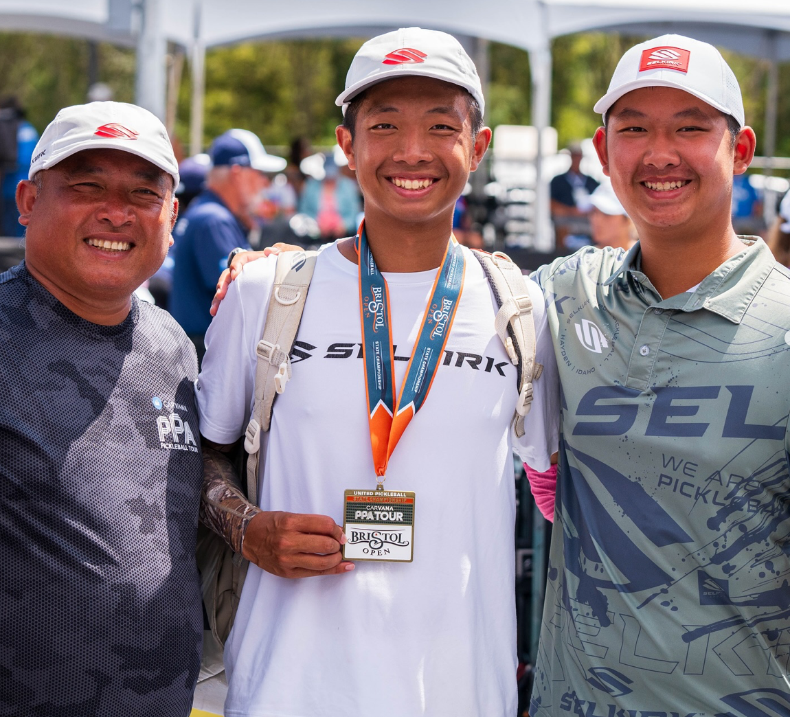 Pickleball player Quang Duong celebrating with teammates after winning gold in men’s doubles, holding his medal.