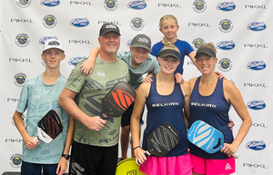 The Lund family stands on a podium holding their Selkirk pickleball paddles. 
