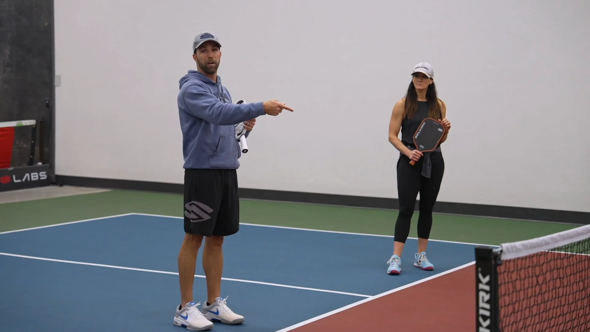 A pickleball coach instructing a student on the court.