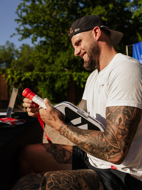 A man adds new grip tape to a Selkirk paddle. 