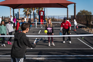 Children practicing pickleball with an instructor on a court.