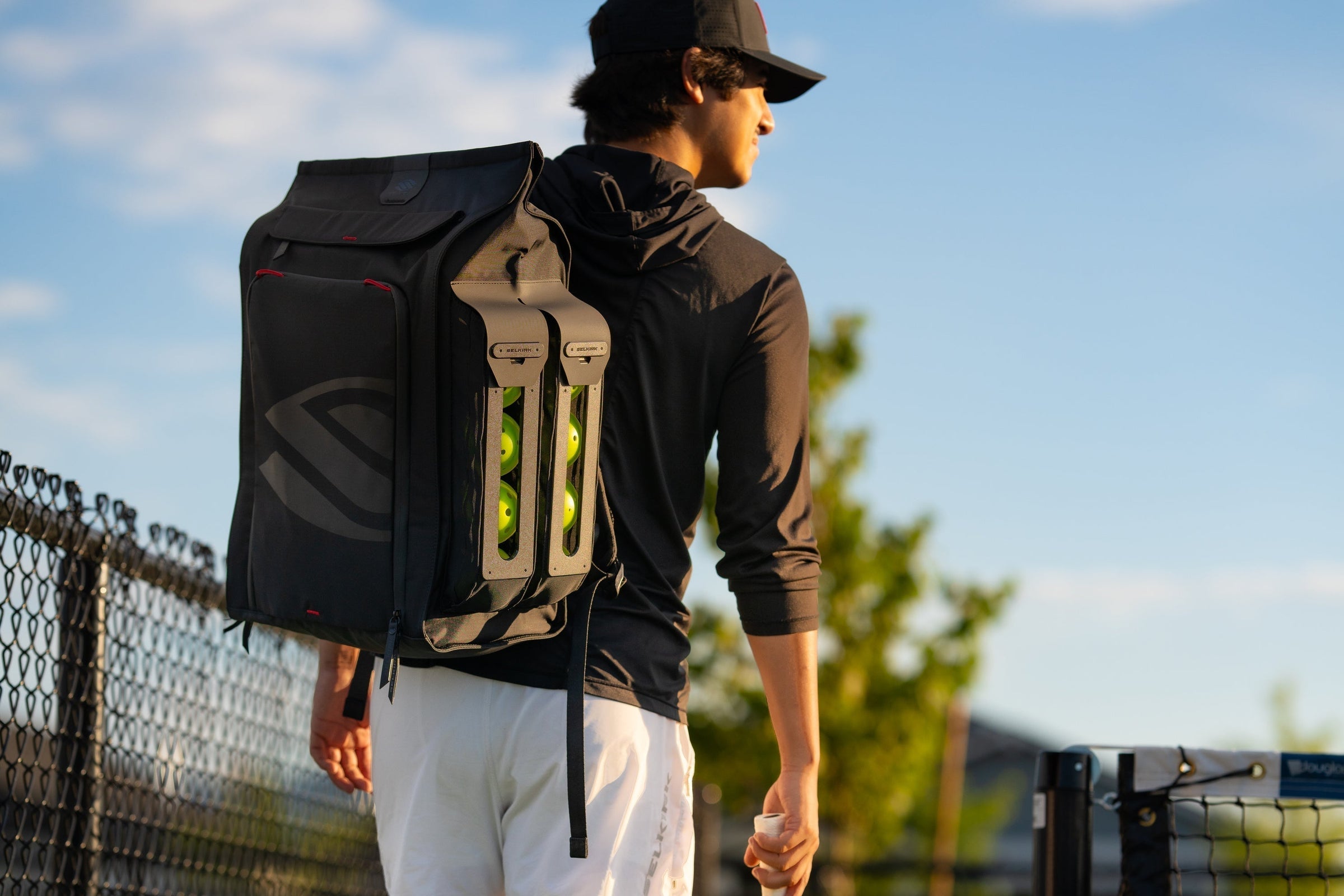 Pickleball player walking across court wearing black pickleball backpack