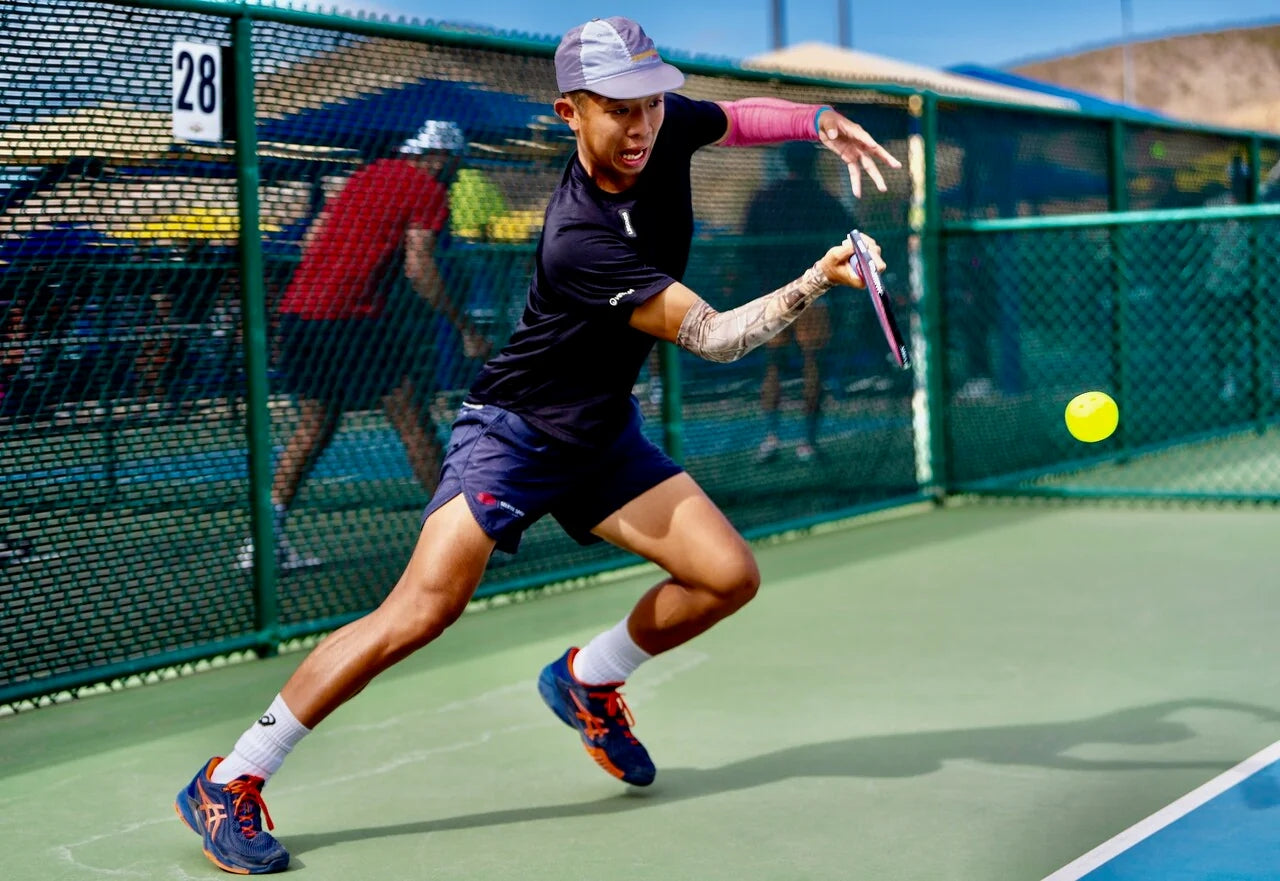A player executing a pickleball shot while in motion on the court.
