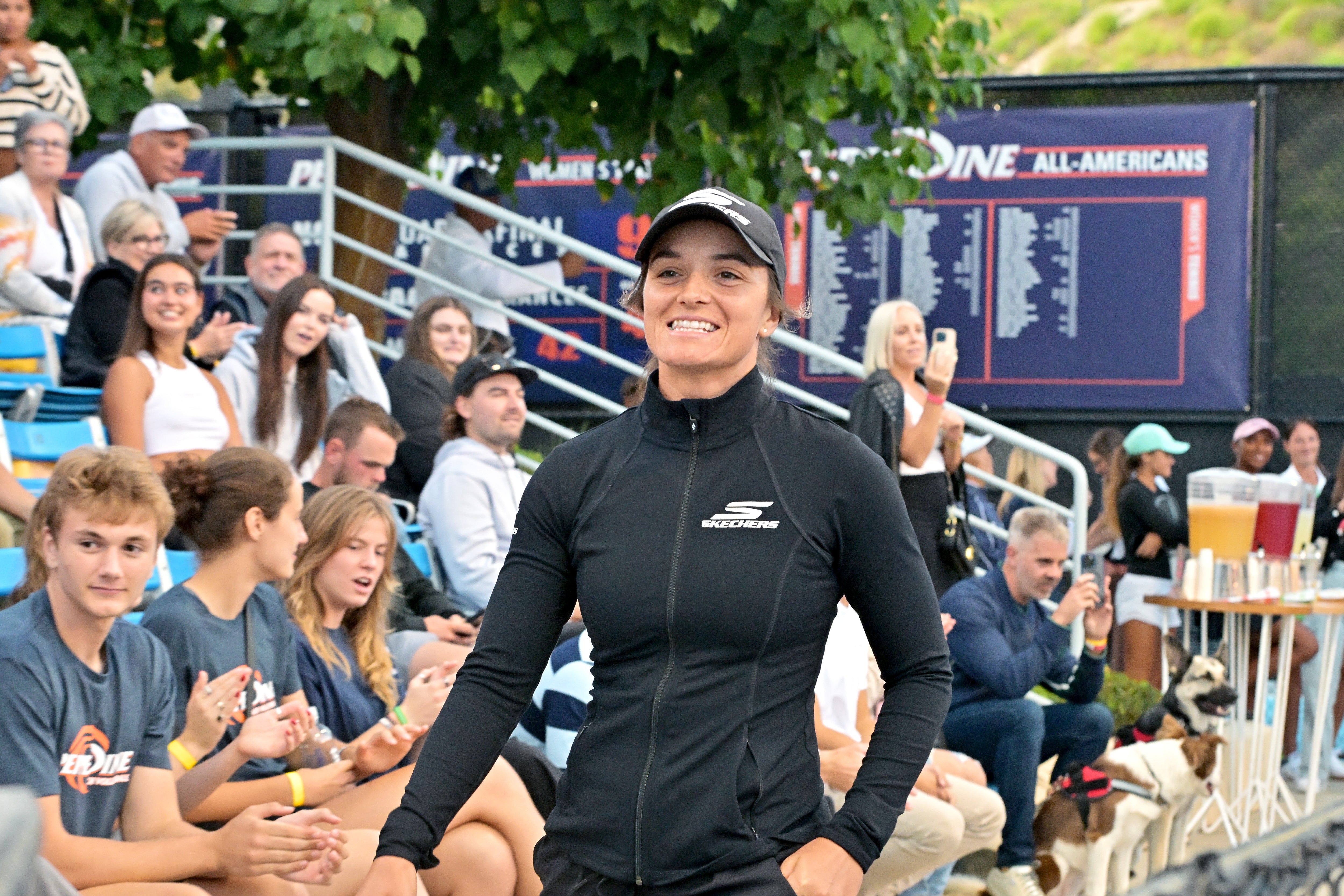 A female pickleball player smiling and walking on the court during a tournament.