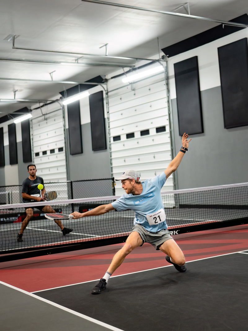 Two people playing indoor pickleball on a court with a modern design.