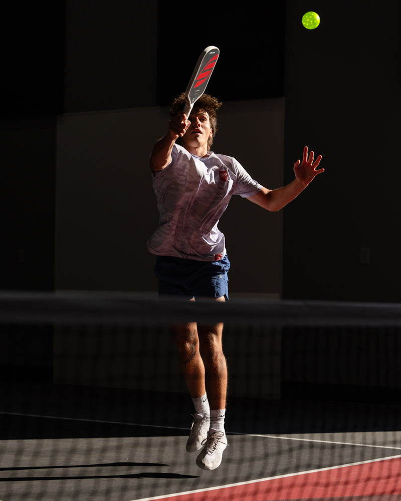 Person playing pickleball on a court with a dark background