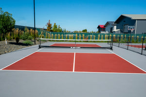 Selkirk Semi-Permanent Pro Pickleball Net set up on a court with red and gray surfaces.