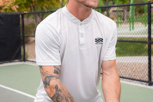 A man wearing a white Selkirk TruWear Vortex Lifestyle Collared Polo, preparing to play pickleball.