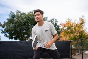 Man playing pickleball in Selkirk TruWear Men's Cardinal Workout Shirt, color black.