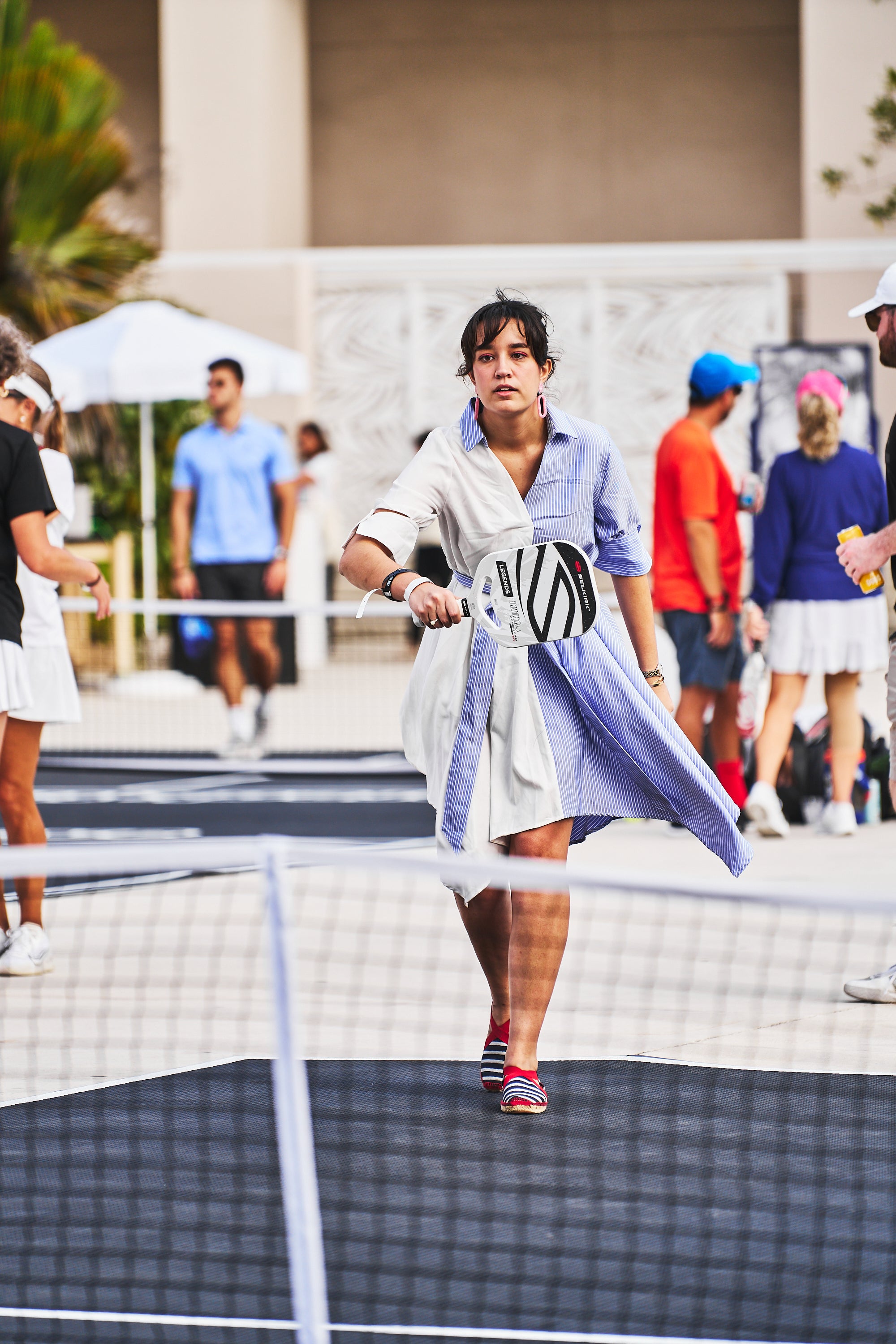 A player in a blue and white outfit holding a pickleball paddle at a pickleball event.