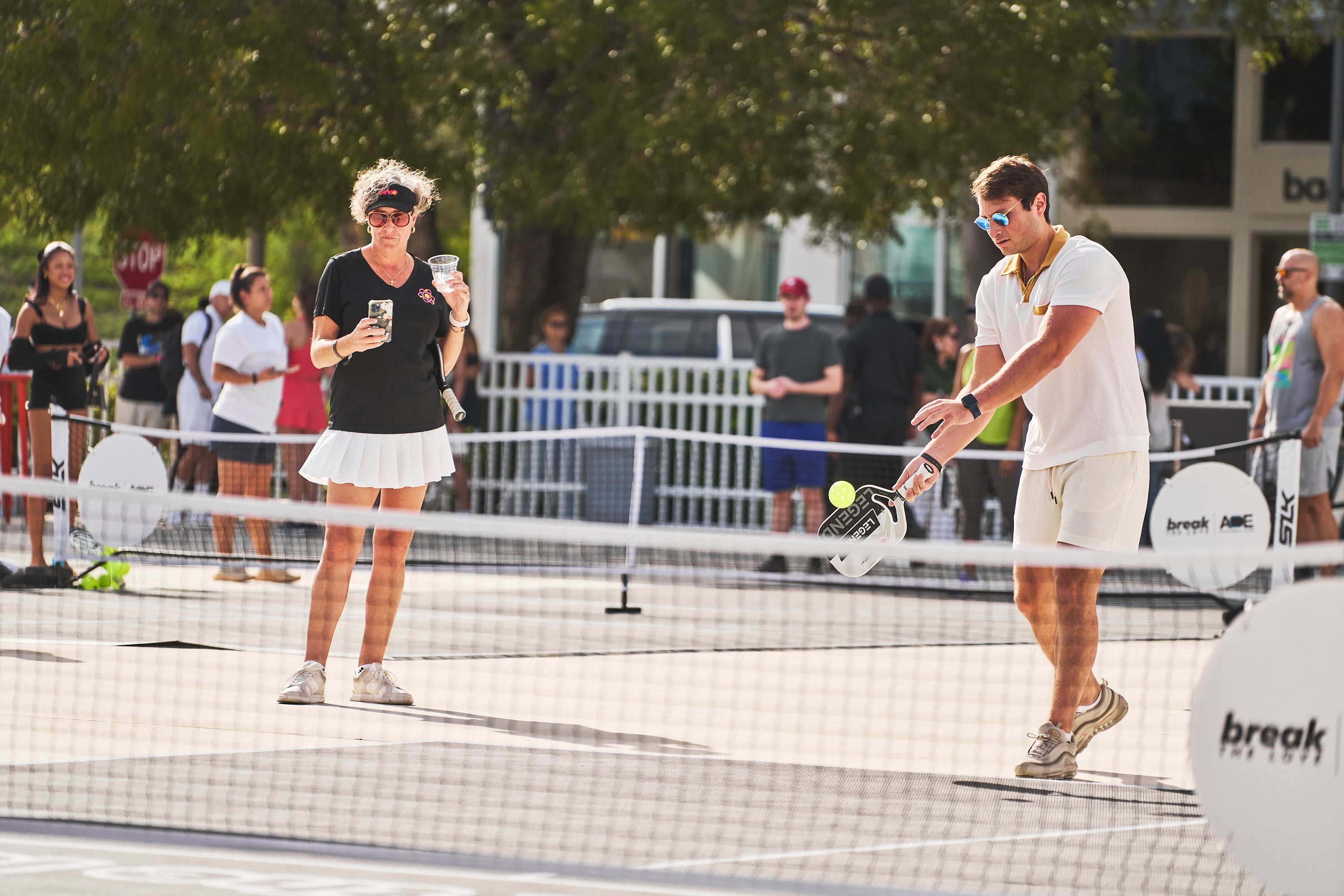 A man and woman playing pickleball at the PICKLEBASEL event in Miami.