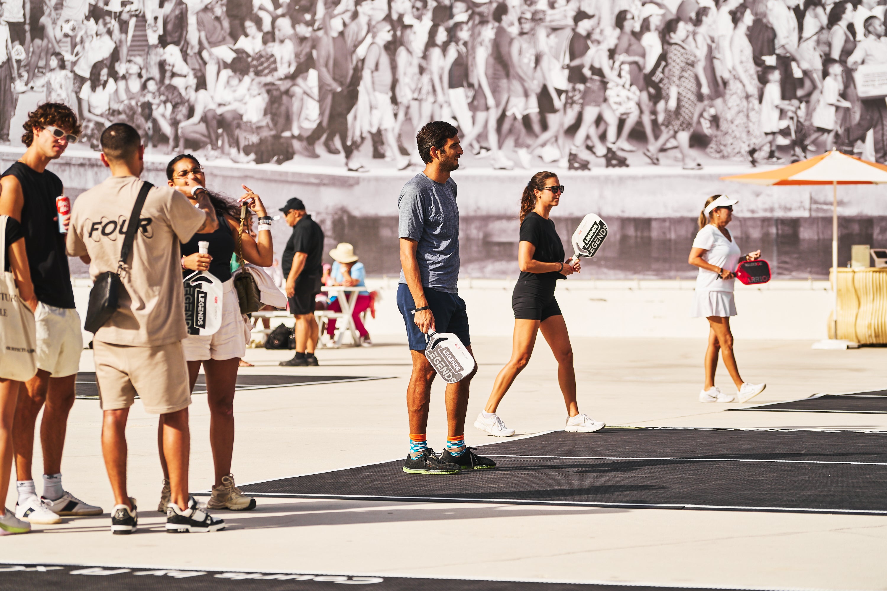 Participants playing pickleball at the PICKLEBASEL event in Miami, with a crowd in the background.