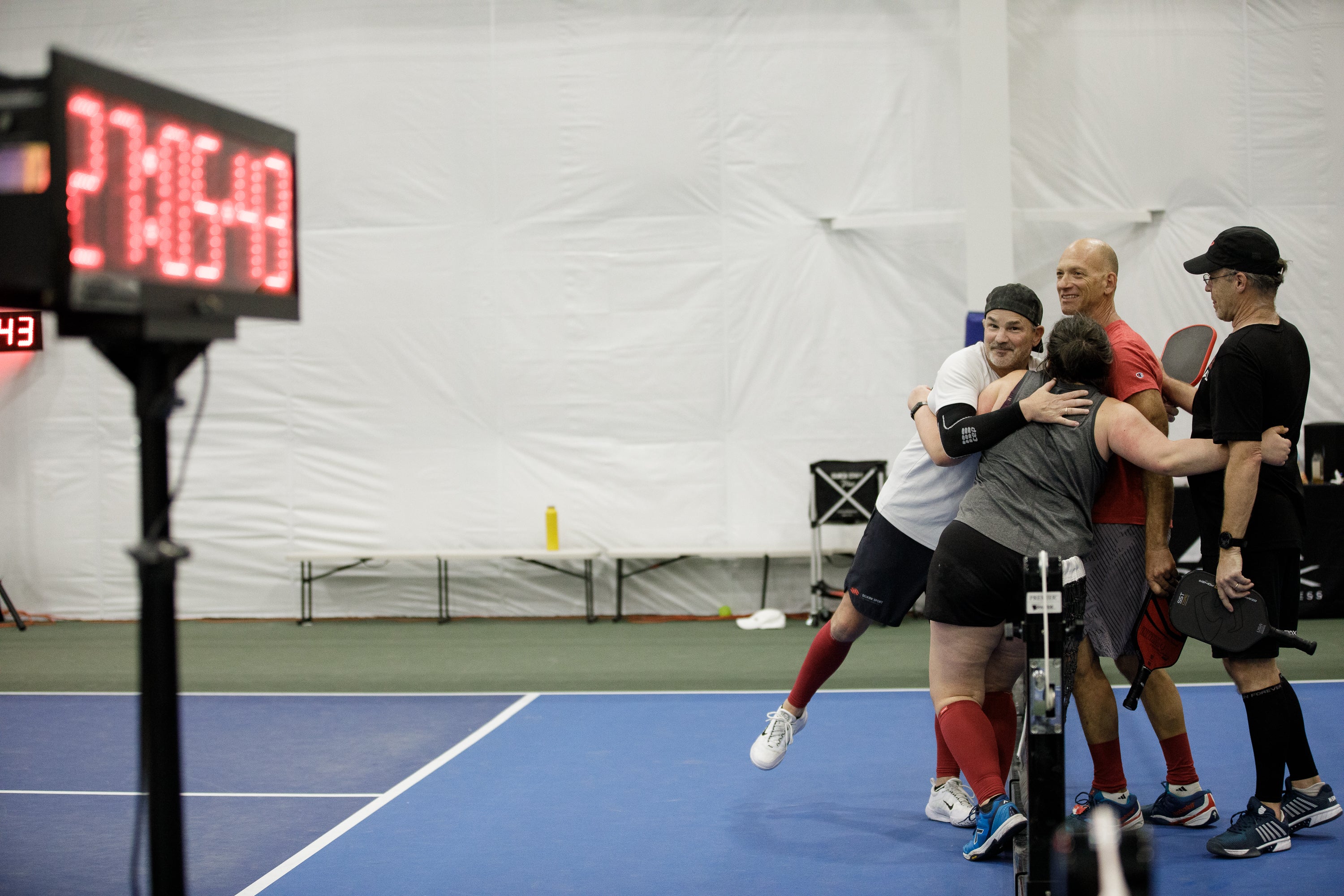 Participants celebrating during a pickleball world record attempt, with a timer showing 70:49.