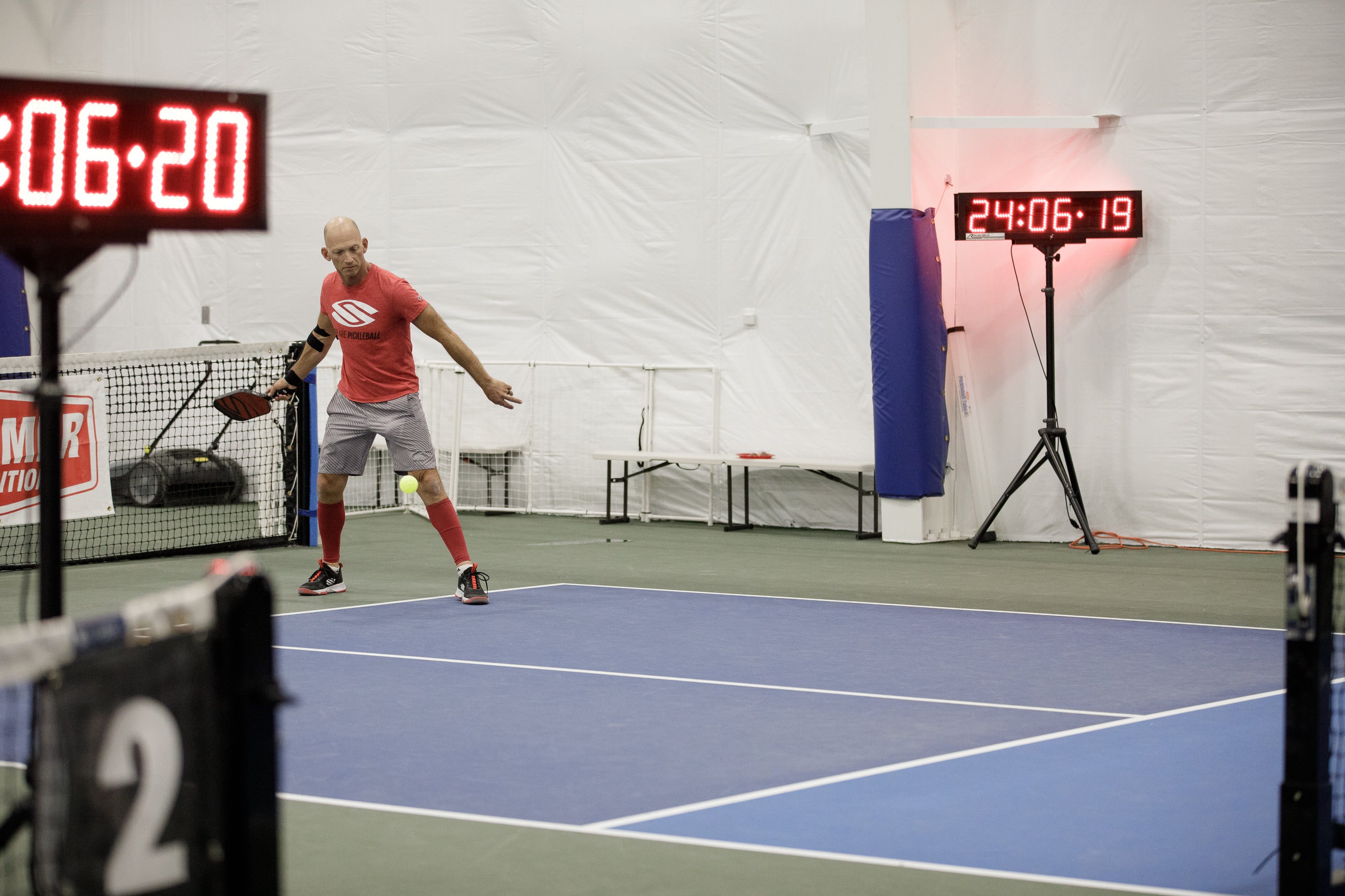 Dave Cook playing pickleball during the Guinness World Record attempt, with timers visible in the background.