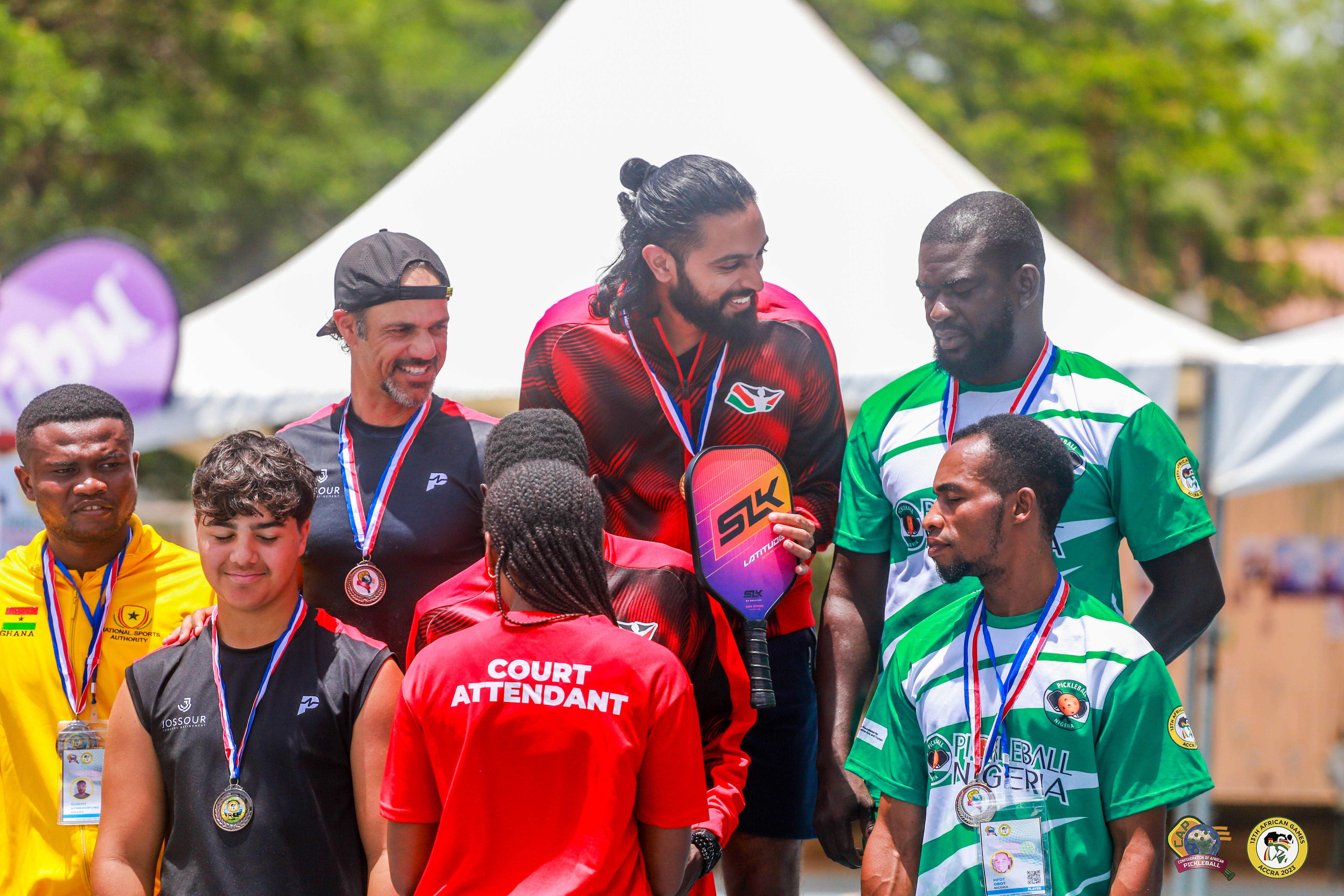 Athletes celebrating at the 13th African Games, wearing medals and holding a pickleball paddle.