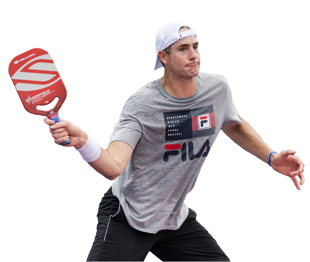 John Isner in gray FILA shirt with SPORTSWEAR BIELLA NYC SEOUL EST.1911 F, swinging red SELKIRK paddle labeled AMPED