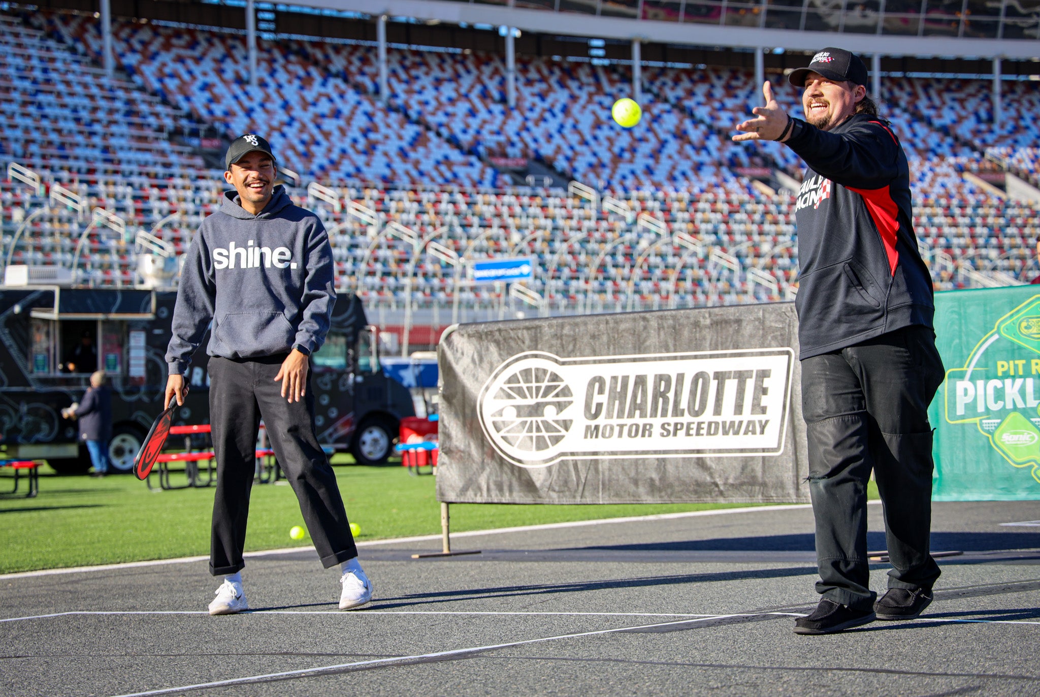 Two NASCAR drivers playing pickleball at Charlotte Motor Speedway