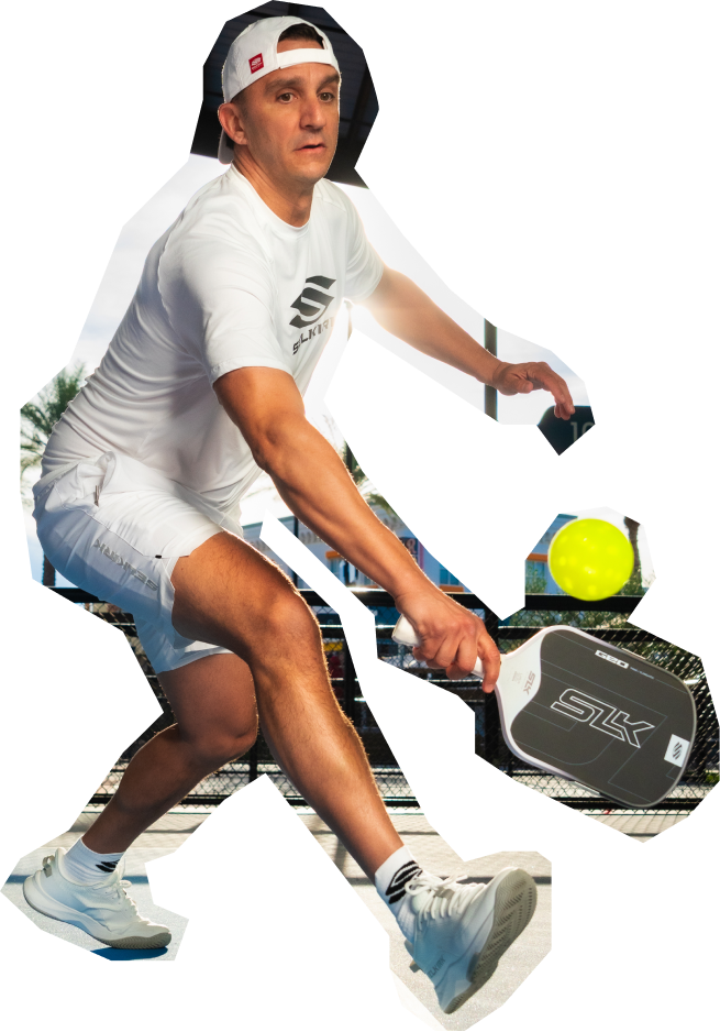 Person playing paddleball with a paddle and ball, wearing a white shirt and shorts.
