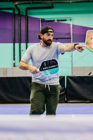 A person demonstrating the SLK by Selkirk x Dude Perfect Evo 2.0 Control Max pickleball paddle on a court.