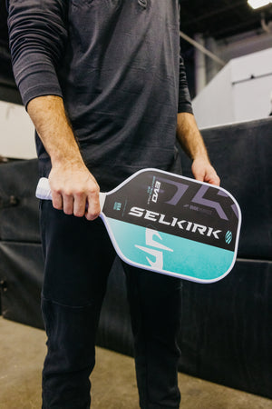 A person holding the SLK by Selkirk x Dude Perfect Evo 2.0 Control Max pickleball paddle, showcasing its design and grip.