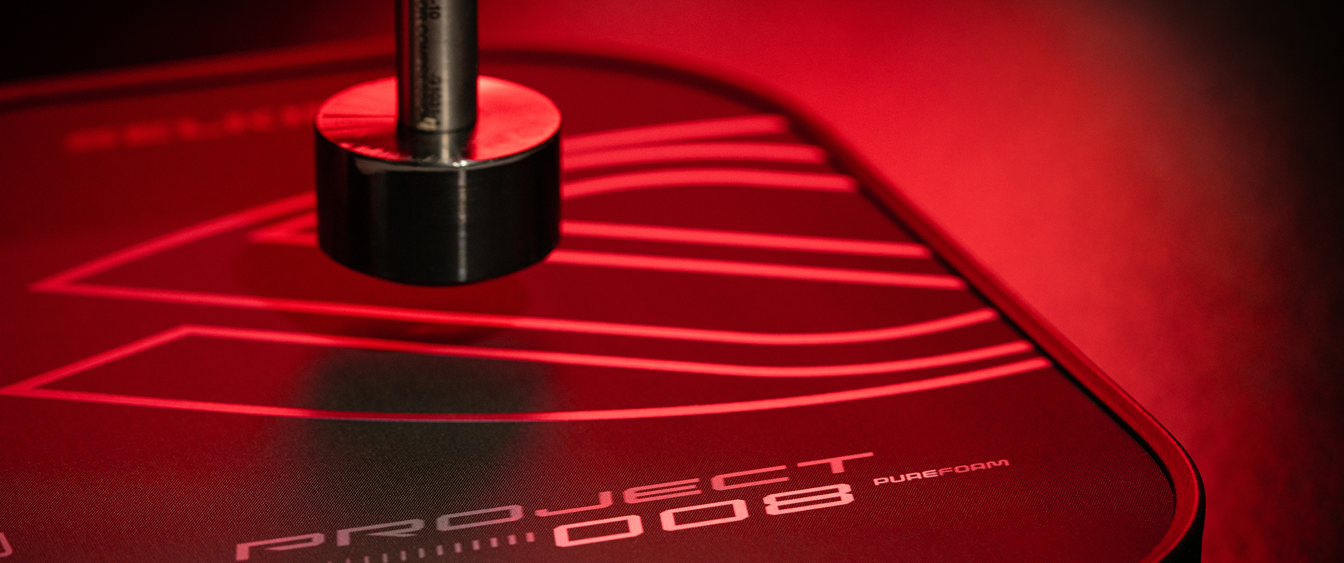 Close-up of the Selkirk Sport Project 008 pickleball paddle featuring the bold Pureform technology design, highlighted under dramatic red lighting to showcase precision engineering and premium surface texture.